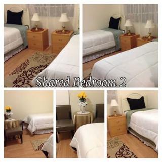 A cozy shared bedroom with twin beds, nightstands, and simple decor.