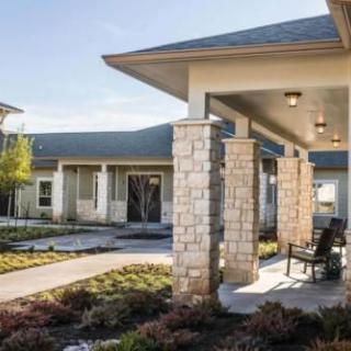 A modern building with stone pillars and a landscaped pathway.