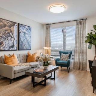 A modern living room with contemporary decor, featuring a comfortable sofa, an armchair, artwork on the walls, and abundant natural light.