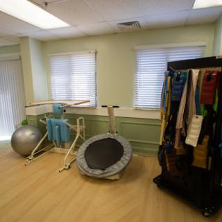 A well-equipped exercise room featuring a trampoline, balance balls, and therapy bands for rehabilitation and fitness activities.
