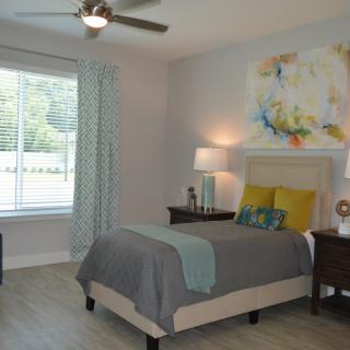 A modern bedroom with a bed, nightstand, and abstract artwork on the wall.