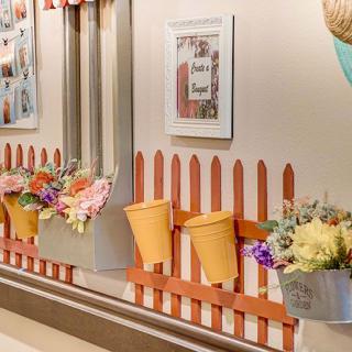 A creatively decorated wall featuring a colorful fence with buckets and flowers.