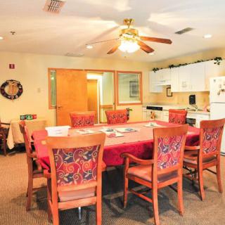 A cozy dining area with a large table, surrounded by chairs and adjacent to a kitchen.