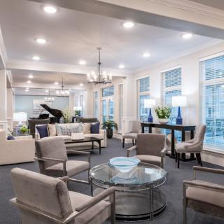A modern living room with elegant furniture, a grand piano, and bright lighting.