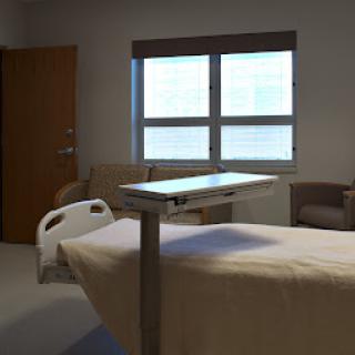 A cozy and clean hospital patient room featuring a bed and a seating area.