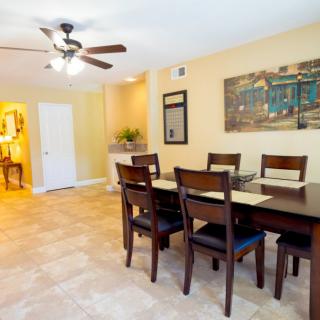 A well-lit dining room with a table, chairs, and ceiling fan.