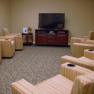 A cozy lounge area with striped chairs arranged in front of a large television.