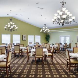 An elegant dining room with chandeliers, neatly arranged tables and chairs.