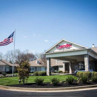 The entrance of Chester, a retirement community, with an American flag and clear blue sky.