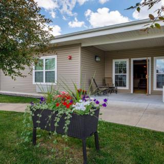 A cozy house with a garden featuring vibrant flowers and a welcoming patio area.