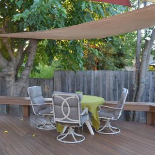 A cozy outdoor patio setup with chairs and a table under a shade sail.