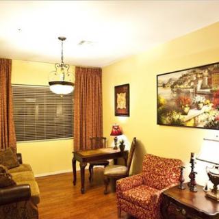 A cozy living room featuring comfortable seating, decorative curtains, and a vibrant painting.