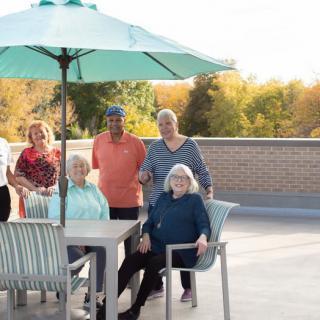 A group of seniors enjoying time together on a patio in autumn.