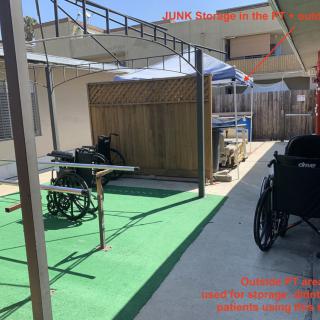 An outdoor pathway with wheelchairs under a shaded area and green carpeting.