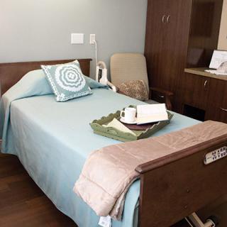 A tidy hospital room with a neatly made bed and a tray on top.