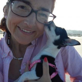 A woman wearing glasses takes a selfie with her dog outdoors.
