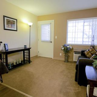 A cozy living room with a sofa, table, and lamp near a large window.