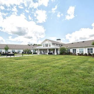 A large house with a well-maintained lawn under a partly cloudy sky.