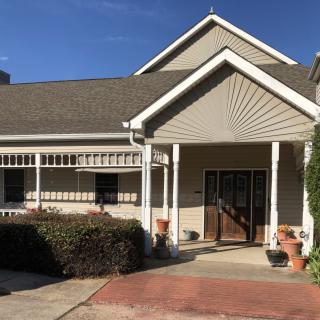 A sunny day view of a residential house with a porch and front yard.