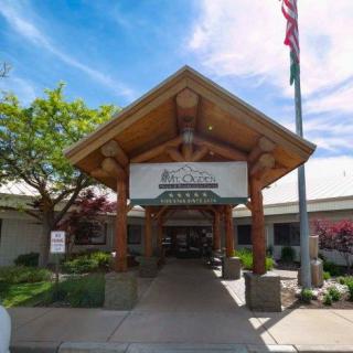 The entrance of a healthcare facility with a wooden canopy and a clear blue sky.