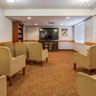 A comfortable conference room with beige chairs facing a large television.