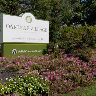 A landscaped garden with a sign reading 'Oakleaf Village'.