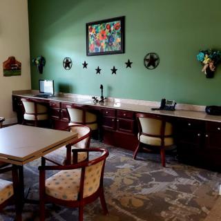 A cozy office workspace with multiple desks, chairs, and a green accent wall featuring decorative artwork.