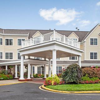 A large residential building with a landscaped entrance and circular driveway.