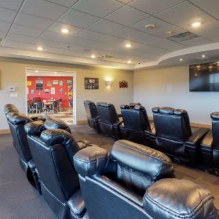 A modern home theater room featuring plush recliner chairs and a large TV screen.