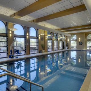 A luxurious indoor swimming pool with large windows and reflective water.