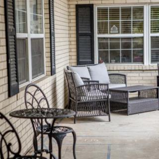 A cozy patio with wicker seating and a small metal table set against a brick wall.