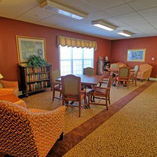 A cozy reading room with chairs, a table, and bookshelves.