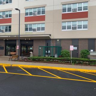 Entrance of a modern apartment building with marked parking spaces.