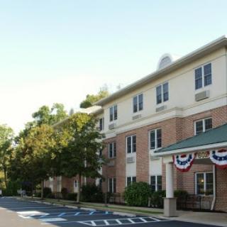 A multi-story residential building with decorative flags and a landscaped parking lot.