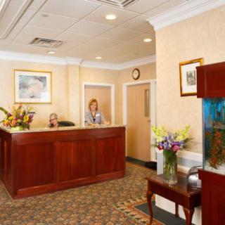 A professional reception area with a wooden desk, flowers, and an aquarium.