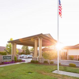 A building entrance with a flagpole during sunset, surrounded by well-maintained landscaping.