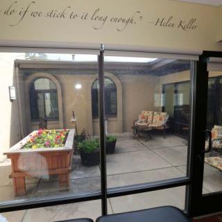 View of a cozy courtyard through glass doors with comfortable seating and a garden table.