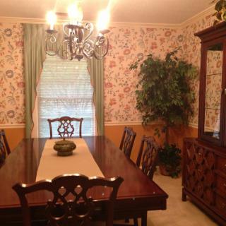 A traditional dining room with a large wooden table, chairs, and a chandelier.
