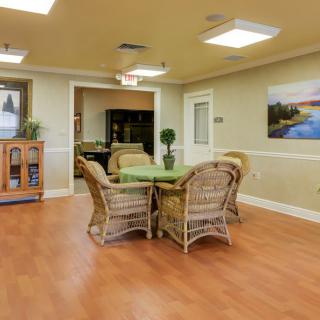 A cozy dining area featuring a round table surrounded by wicker chairs, set on a warm wooden floor with decorative wall art.