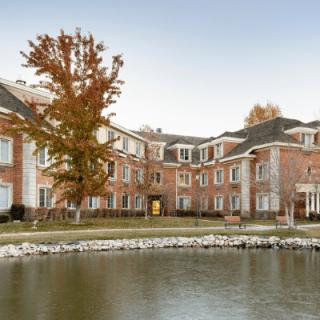 A brick building with a scenic view of a lake and autumn trees.