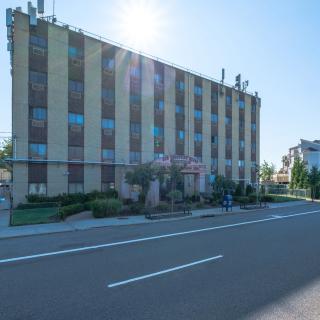 A multi-story building on a sunny day with clear blue skies, adjacent to a street.