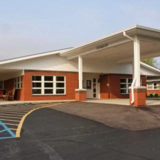 The image shows a single-story brick building with a covered entrance, resembling a school or educational facility.