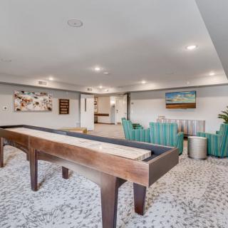 A modern game room featuring a shuffleboard table, comfortable seating, and stylish decor.