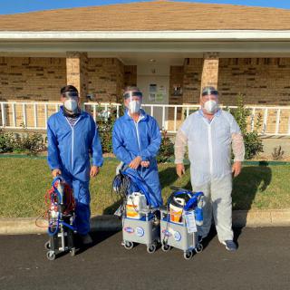 A team of workers in protective gear ready for a cleaning job outside a home.