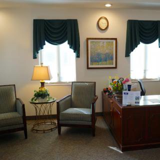 A well-lit office waiting area featuring comfortable seating, a desk, and decorative elements.