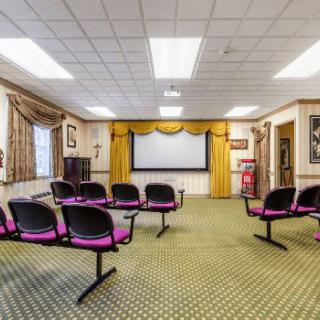 A small conference room with a projector screen and rows of chairs.