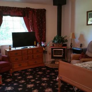 A cozy living room with a TV, carpet, and comfortable seating.