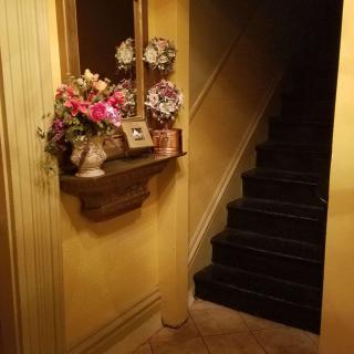 A cozy hallway with a vase of flowers, decorative plates, and a staircase leading upwards.