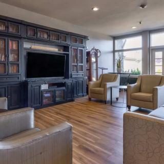 A cozy living room with a large TV, bookshelves, and comfortable armchairs.