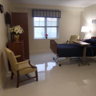 A clean and well-lit hospital room with a bed, chair, and decorations.